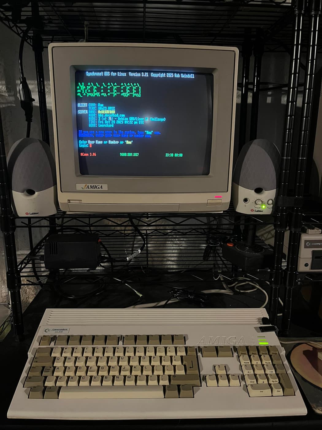 Amiga 1200 beneath a CRT monitor displaying Synchronet BBS with colorful ASCII art