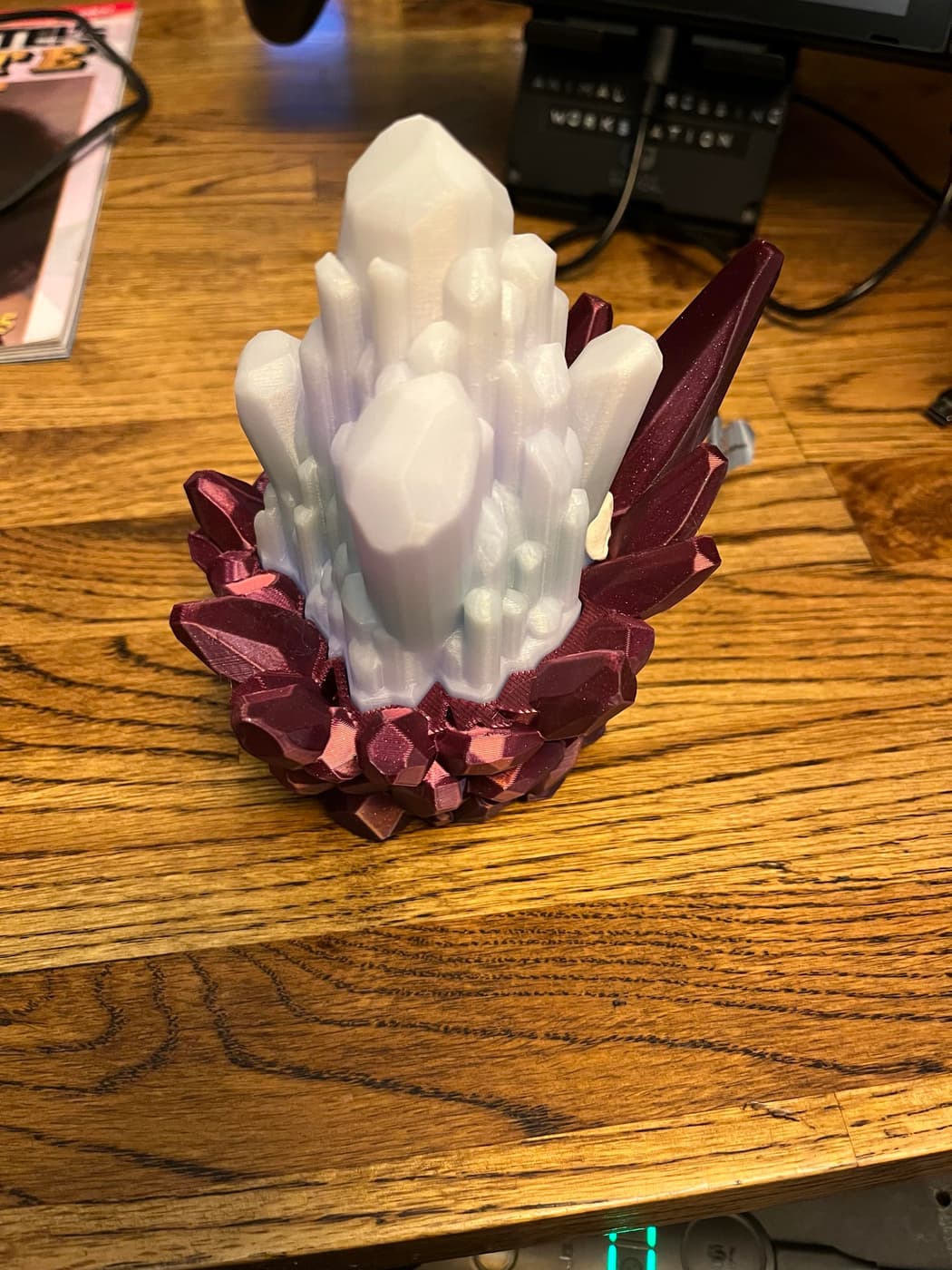 A 3D-printed crystal formation with white/translucent top and crimson base on wooden surface