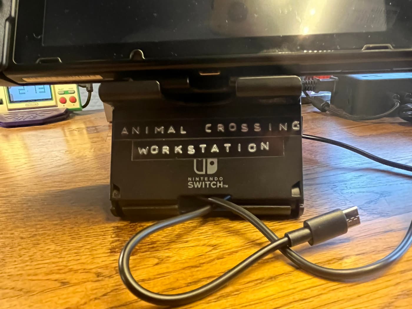 A Nintendo Switch in a black stand labeled "ANIMAL CROSSING WORKSTATION"