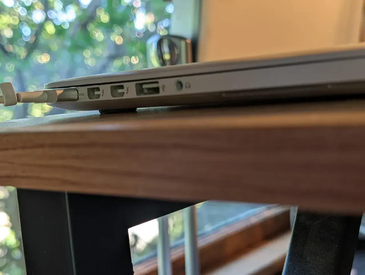 Side profile of the MacBook Pro's port edge, raised slightly off the desk on a black 3D-printed foot