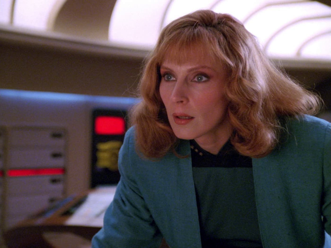 Close-up of Dr. Beverly Crusher looking alarmed as she realizes something is wrong