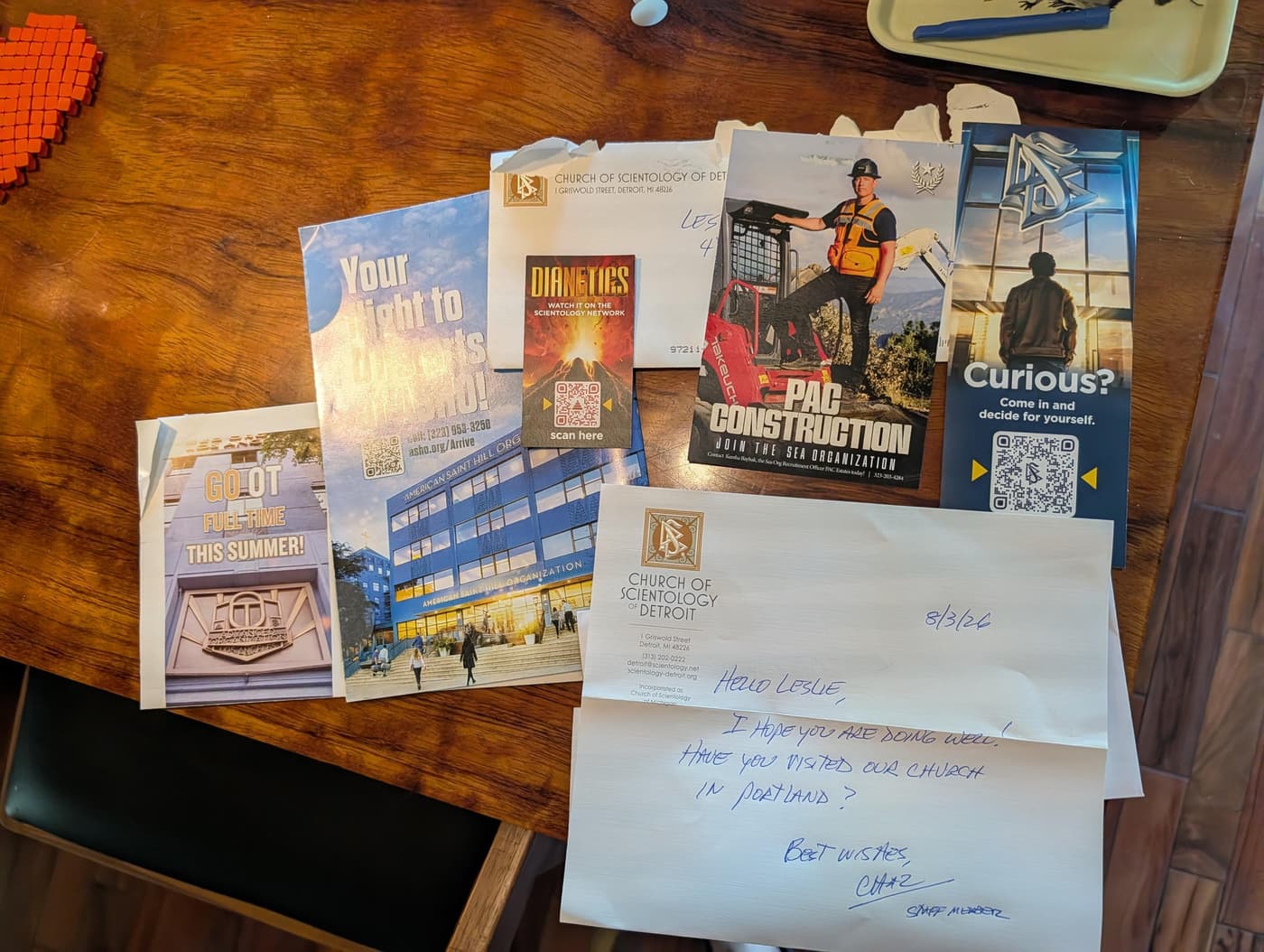 A handwritten note and brochures from the Church of Scientology, including recruitment flyers and information about Dianetics.